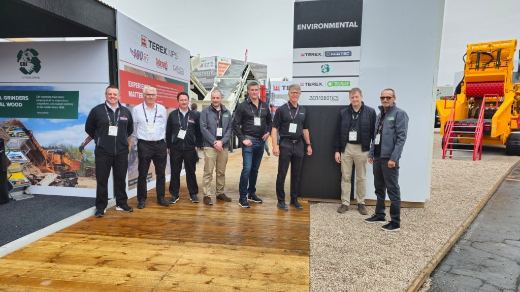 A group of people pose for a photo at a trade show booth