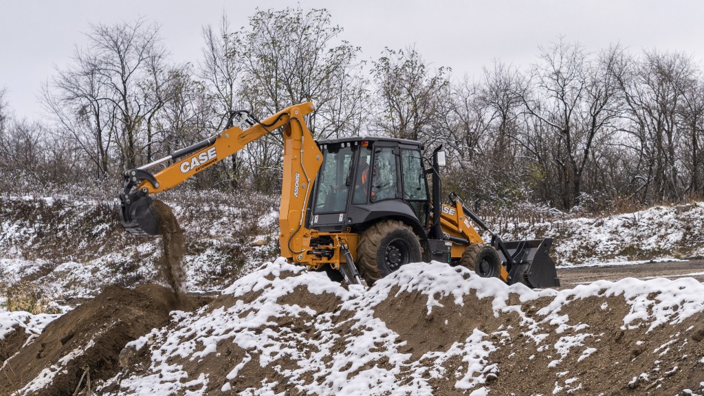 A backhoe loader dumps a bucket of dirt on a job site