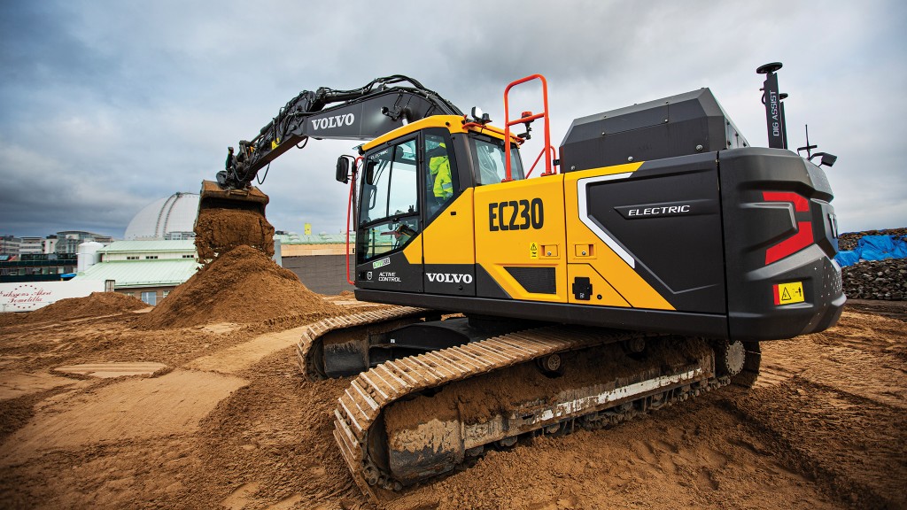 An electric excavator dumps a bucket of dirt on a job site