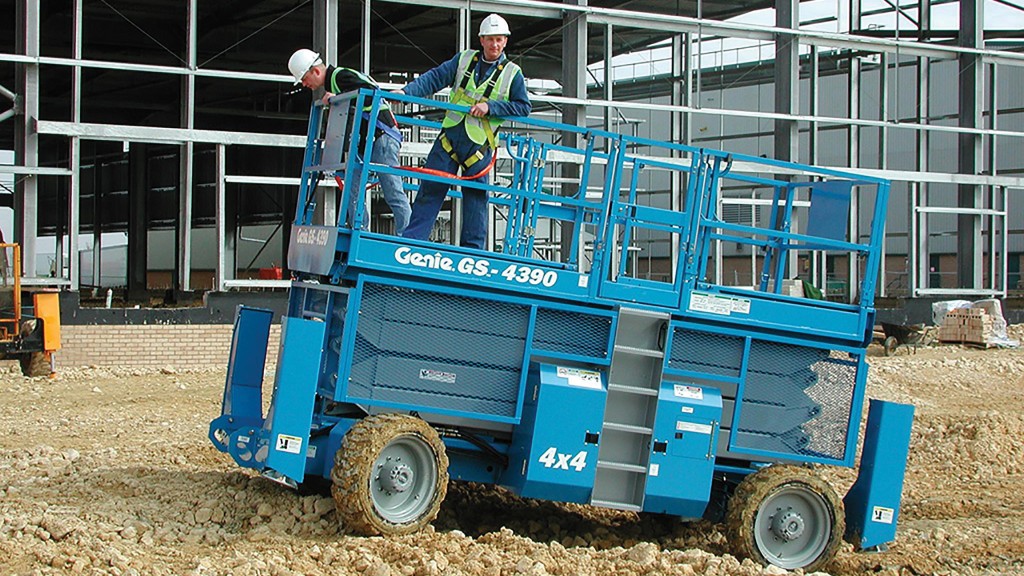 A scissor lift drives along loose rocks and gravel