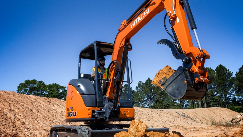 A compact excavator digging in a dirt pile.