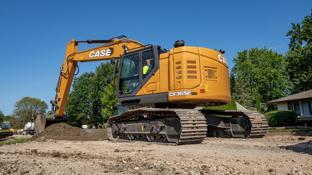 An excavator digs a bucket of dirt on a job site