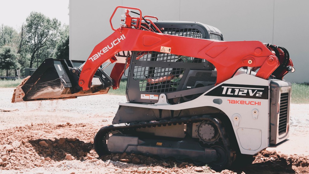 A compact track loader lifts a bucket of dirt on a job site