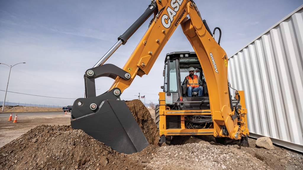 A backhoe loader digs a hole near a storage container