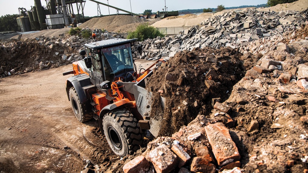 A wheel loader fills its bucket with dirt and other debris