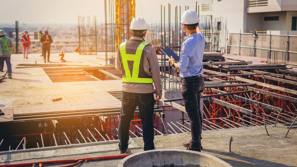 Two workers look at a tabler on a construction site