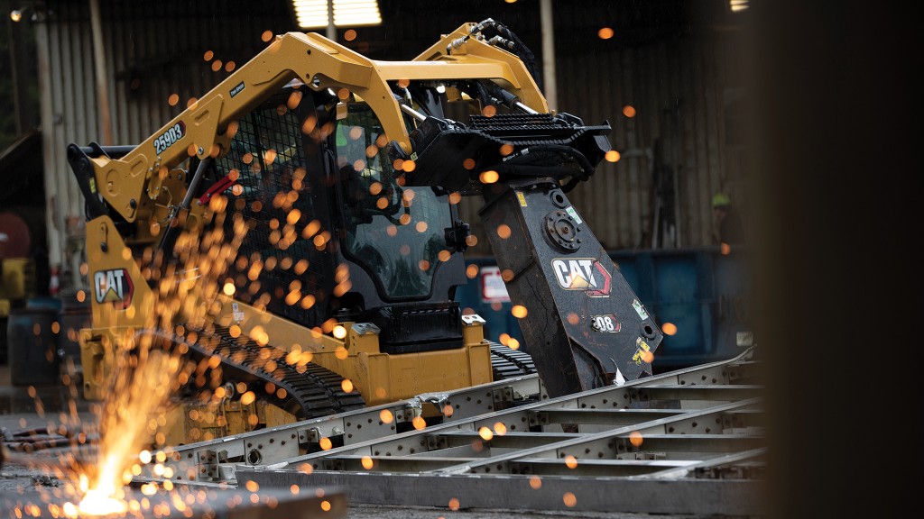 A compact track loader uses a shear attachment on a job site