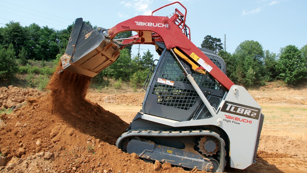 A compact track loader dumps a bucket of dirt onto a pile