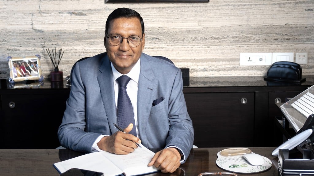 A businessman in a light blue suit sitting at an office desk.