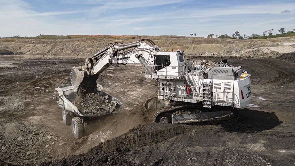 An excavator fills a mining truck with rock