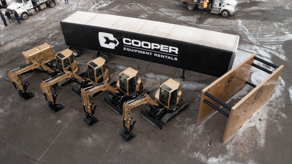 A line of mini excavators parked near a truck