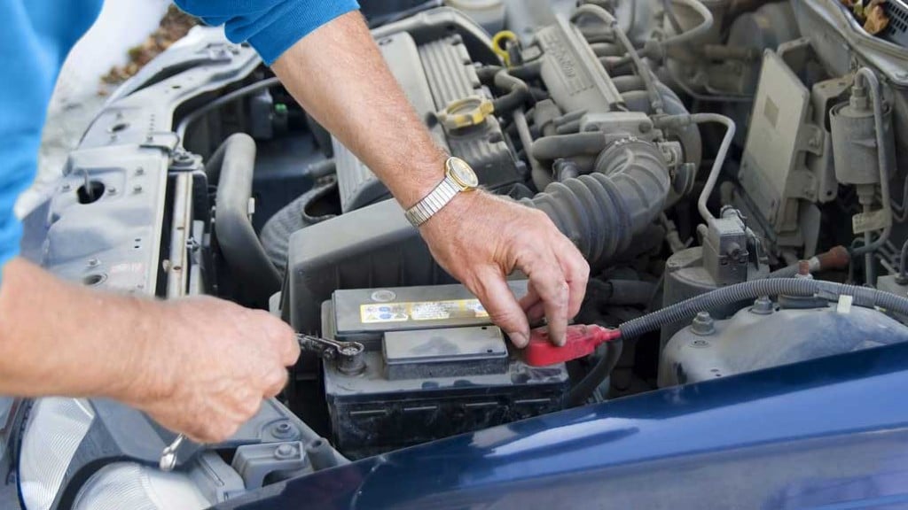 A technician removes a lead-acid car battery