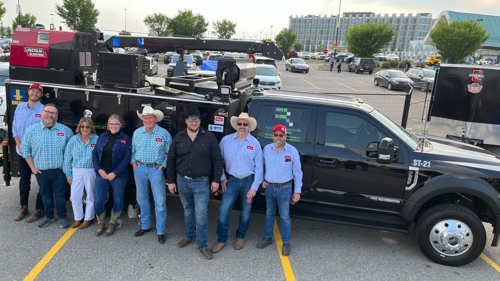 A group of people pose for a photo near a service truck