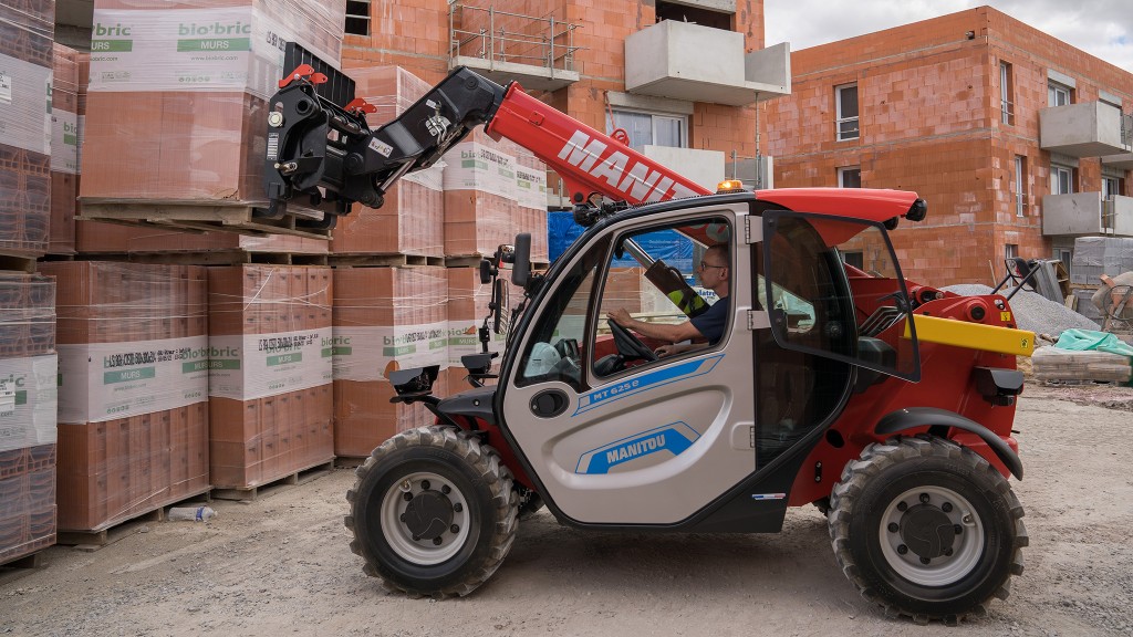 A compact telehandler picks up a pallet of building material