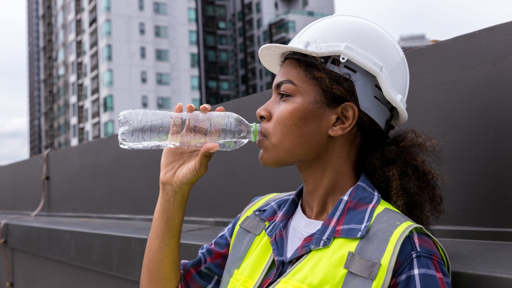 A construction worker drinks water from a plastic bottle