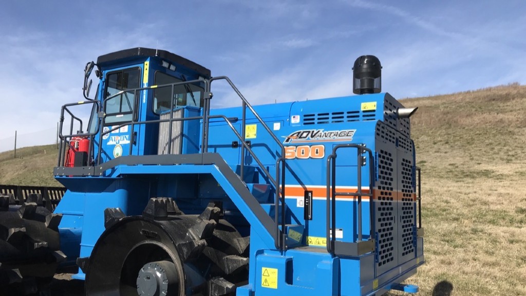 A landfill compactor parked near a hill