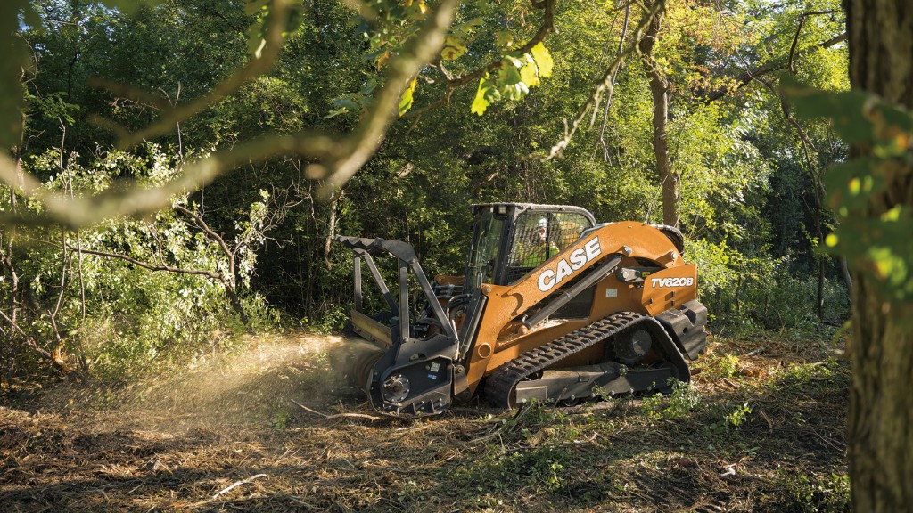 A compact track loader mulching in the woods.