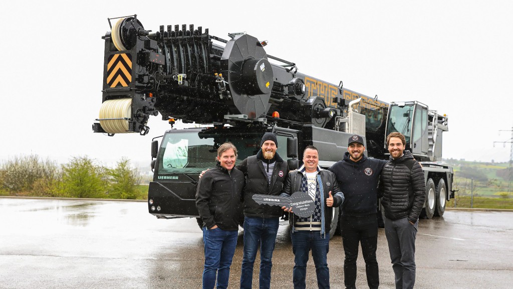 A group of people pose for a photo near a mobile crane