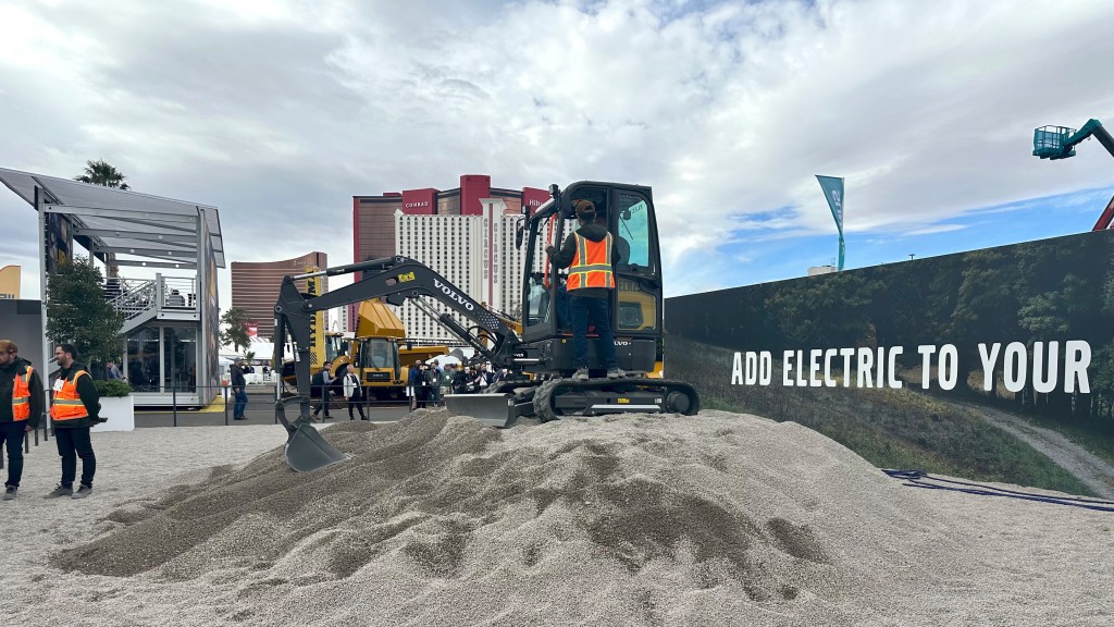 A mini excavator is parked on top of a small mound of sand