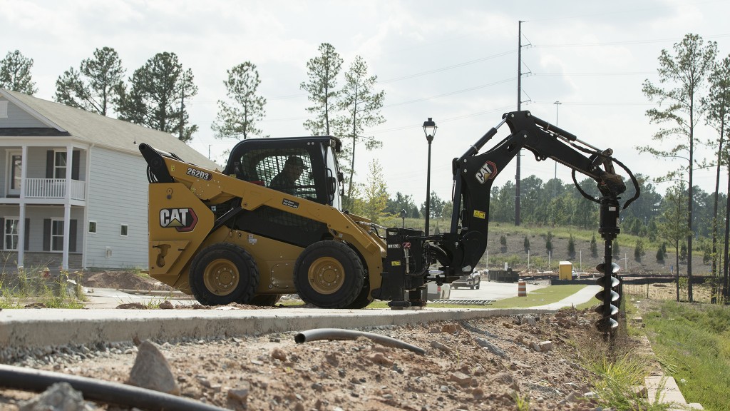 A skid-steer loader uses an auger to drill a hole