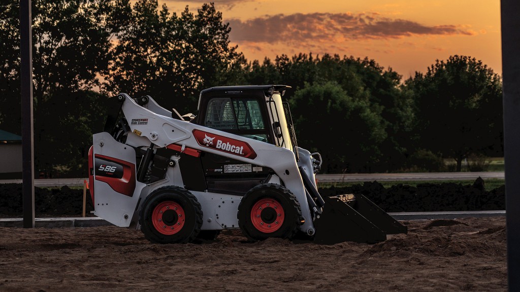 A skid-steer loader is parked at night on a job site
