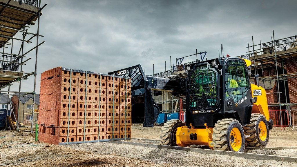 A skid-steer loader moves a pallet of bricks