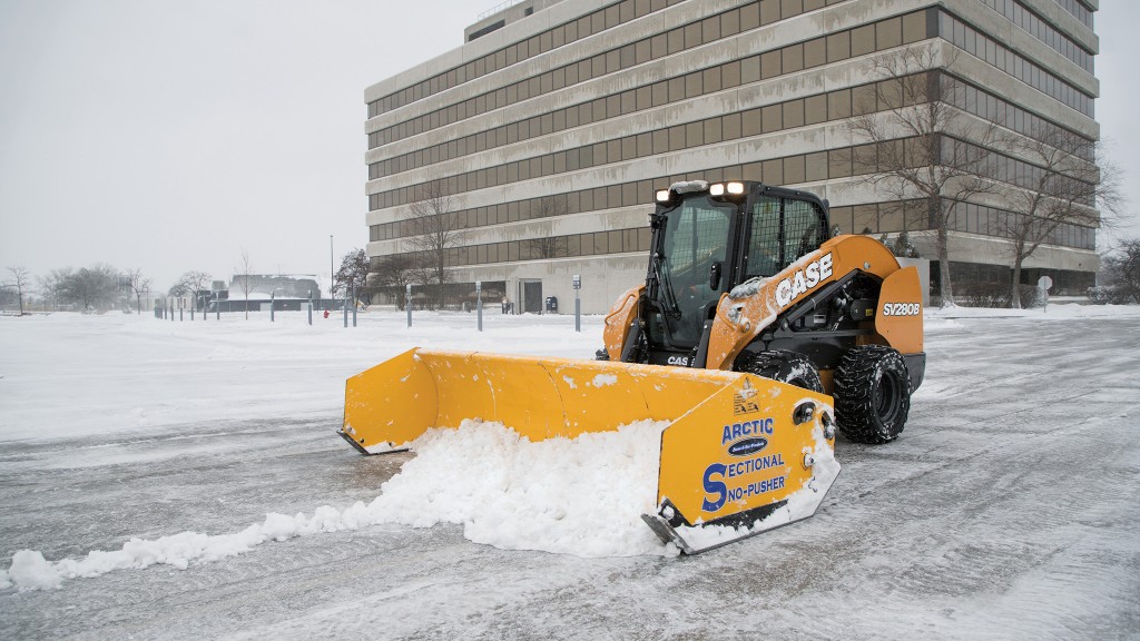 A skid-steer loader plows snow on a road