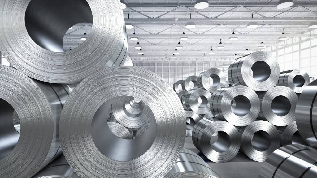 Stacks of rolled steel are stored inside a facility