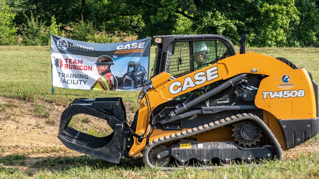 A compact track loader on a grass field.