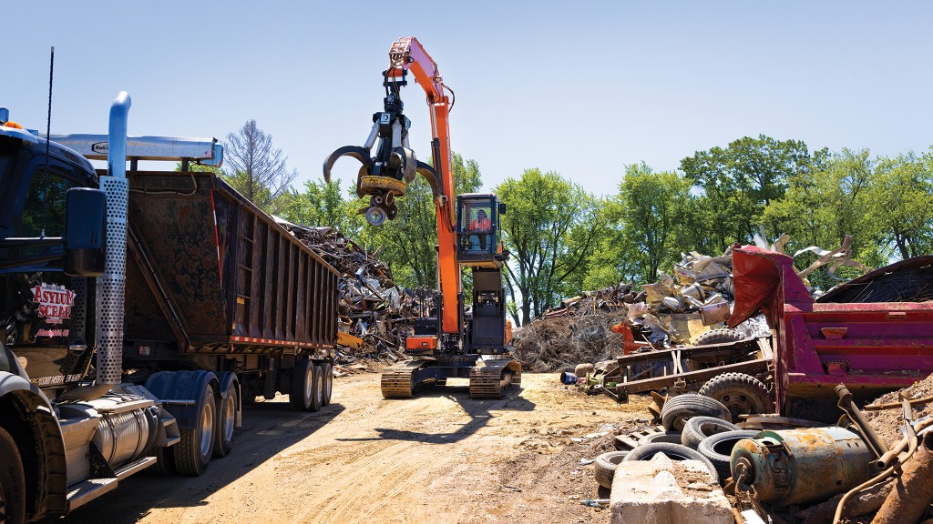 An operator drives a material handler around a scrapyard