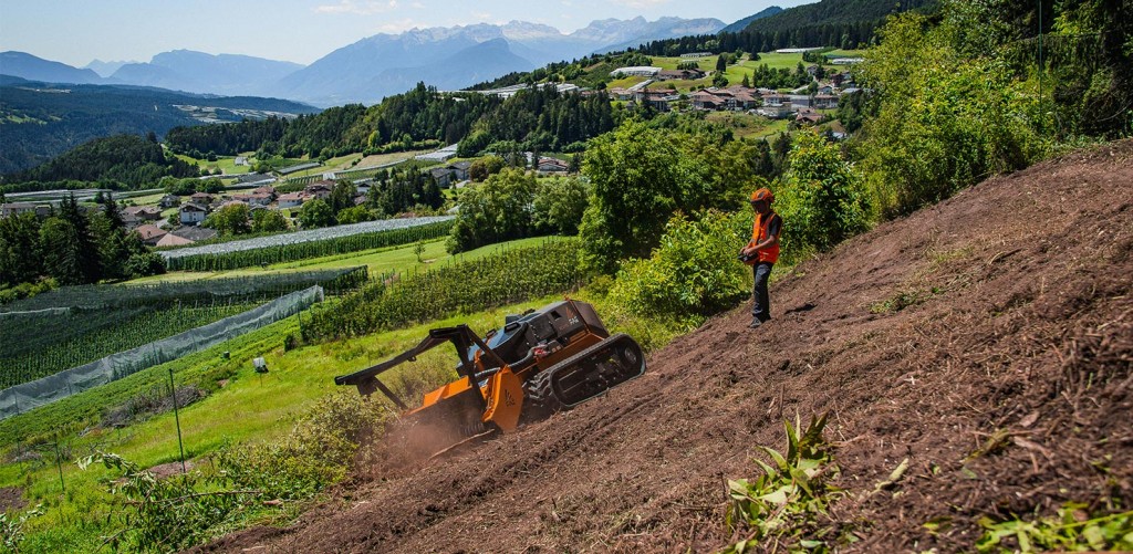 A worker controls a remote-controlled mulcher on a slope.