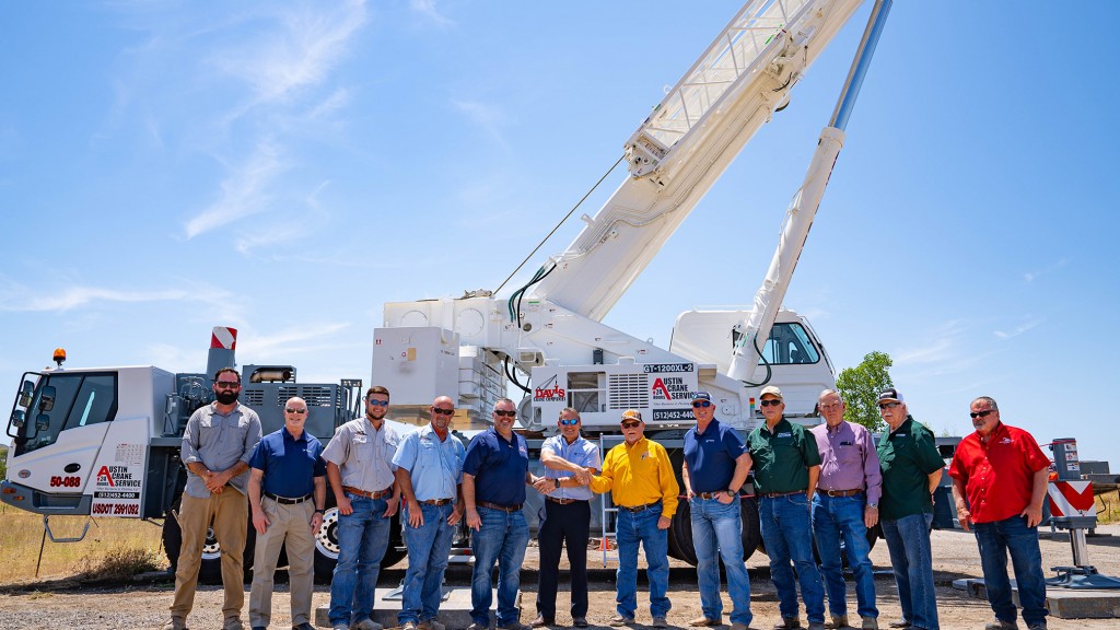 A group of people standing in front of a large crane.