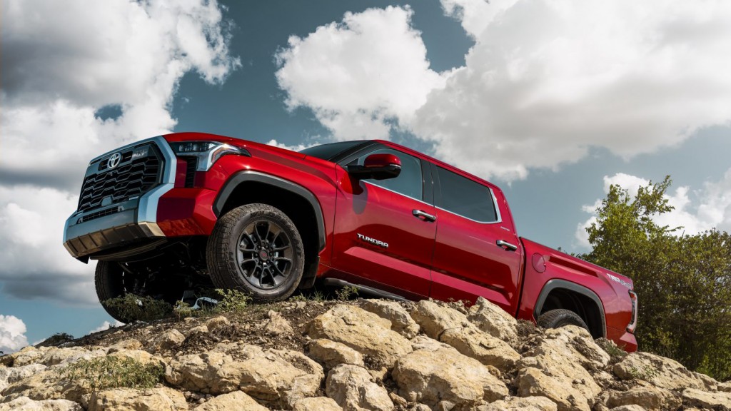 A red pickup sits atop a pile of stones.