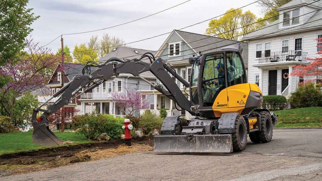 A compact wheeled excavator works on a landscaping job