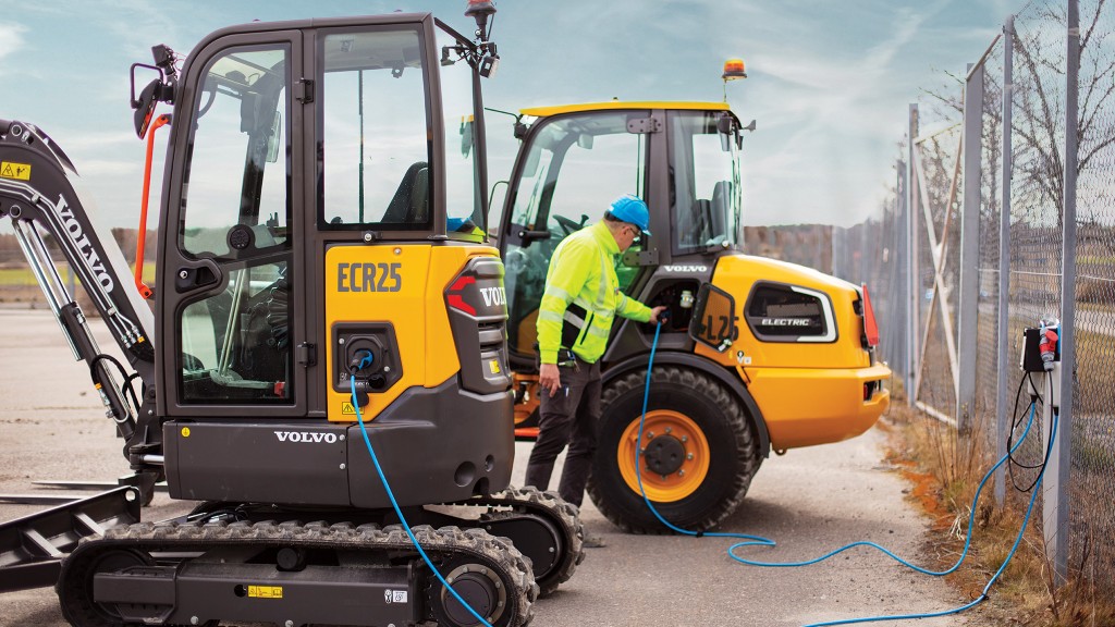 An electric excavator and an electric wheel loader charge at a charging station