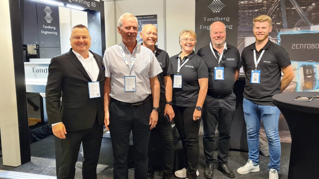 A group of people pose for a photo at a trade show booth