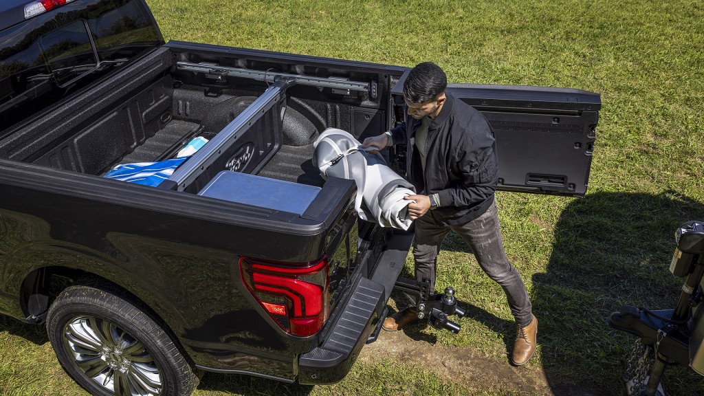 A man loading equipment into a pickup bed through a side-swinging tailgate