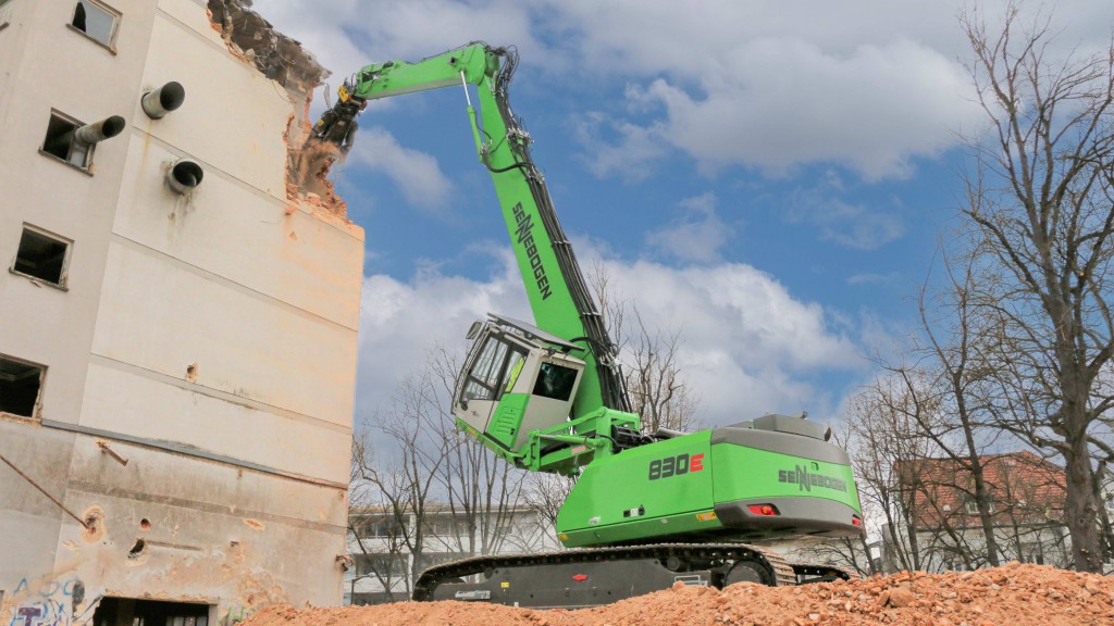 A material handler with a tilted cab demolishes a building