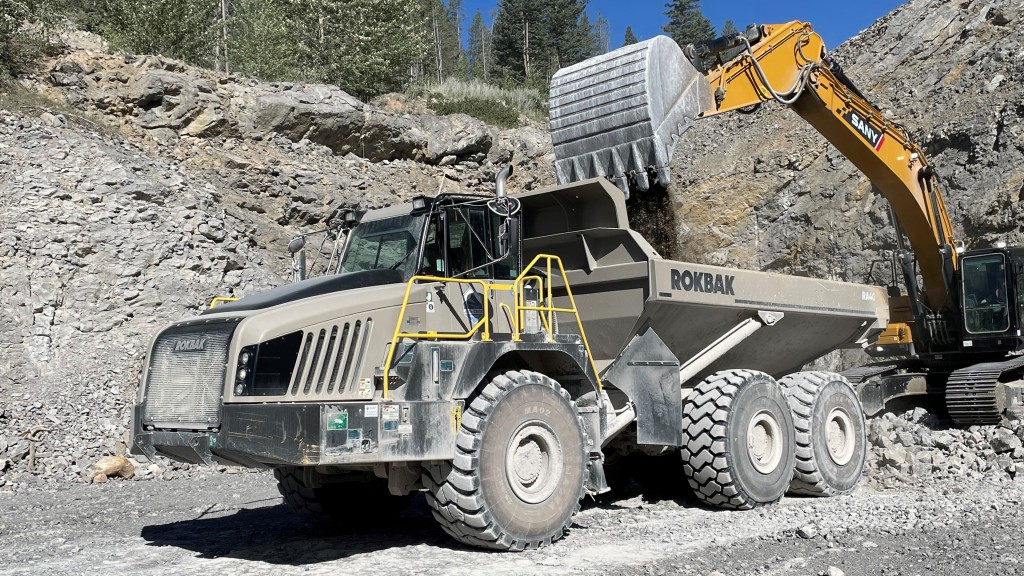 An excavator fills an articulated hauler with aggregate