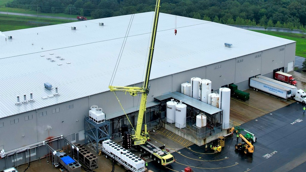 An aerial view of a crane with its boom up next to a factory.