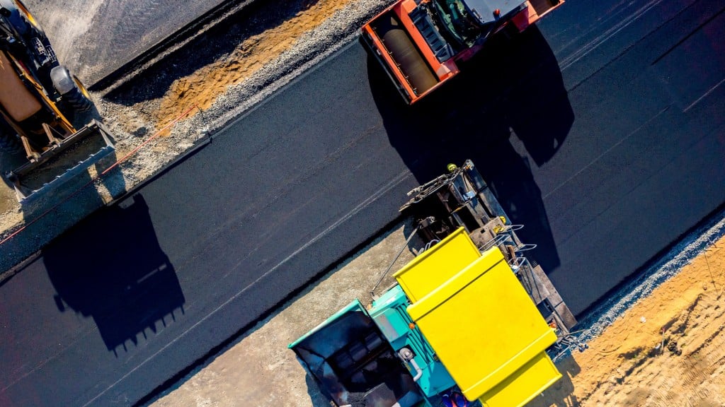 A paver and a roller work on a roadbuilding job site