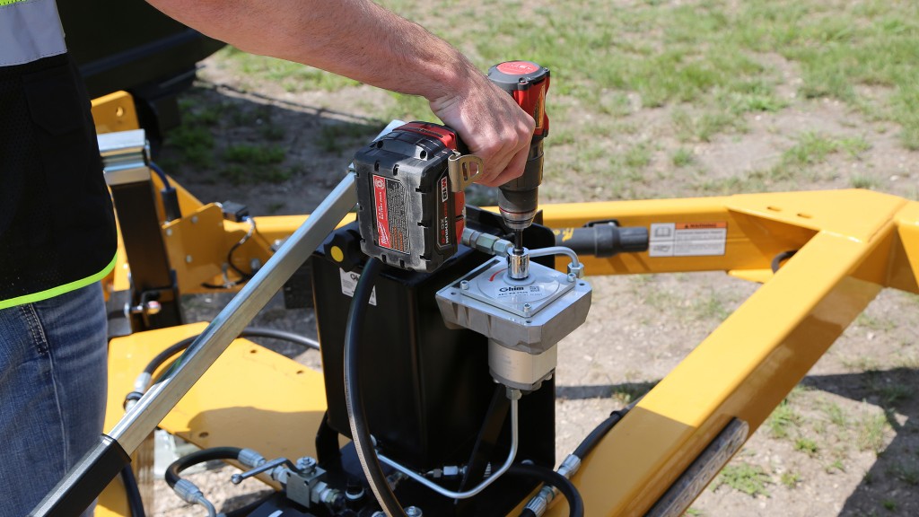 A man runs a pump on a cable trailer using a cordless drill.
