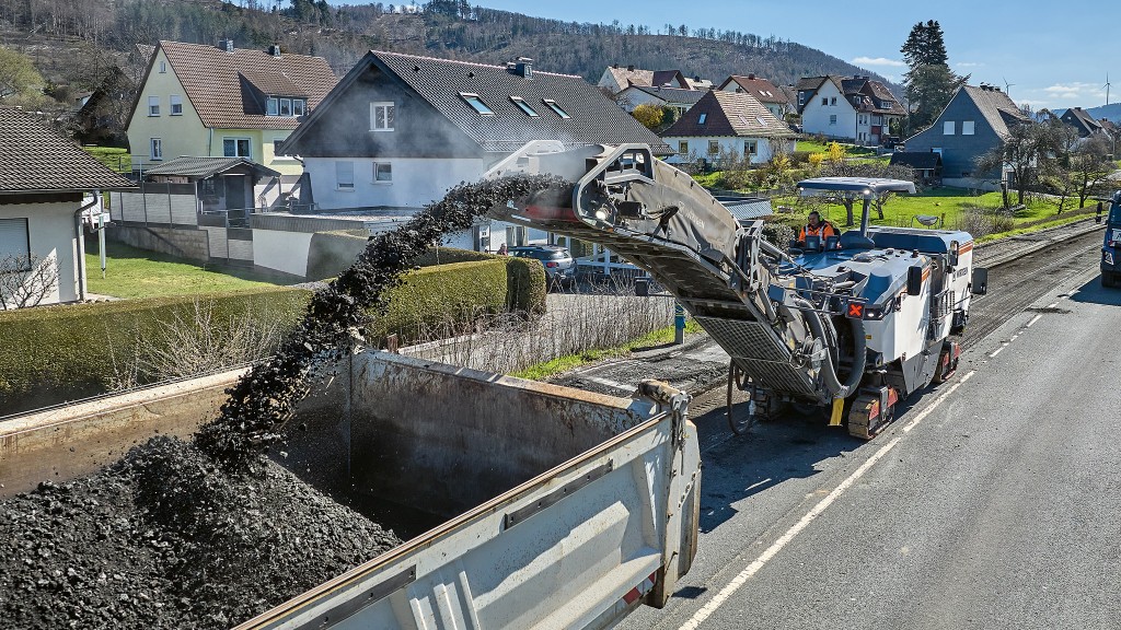 An aerial view of a cold milling machine spraying asphalt into a truck.