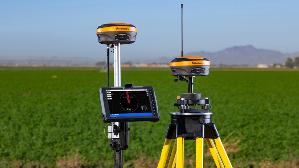 Two GNSS site management tools in front of a green field.