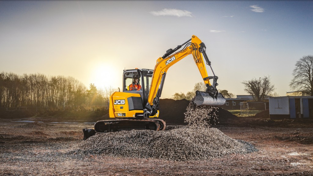 A compact excavator spills rocks from its bucket