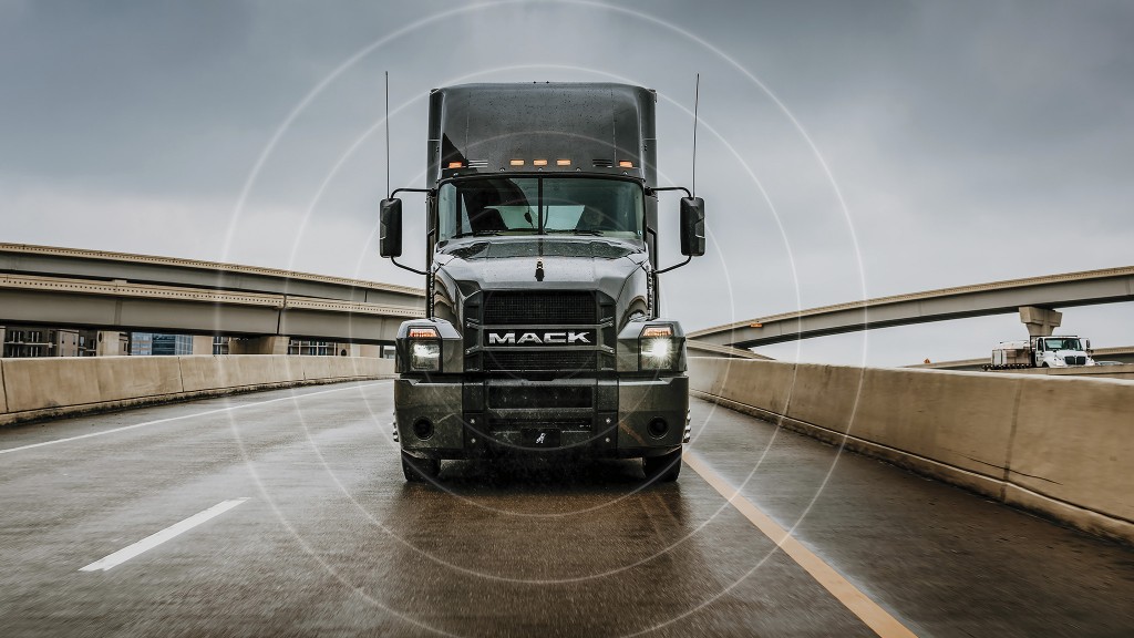 A front view of a tractor-trailer driving on a wet highway.