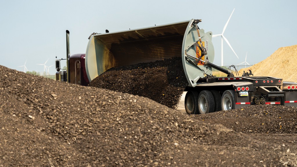 A side dump trailer dumps out material on a job site