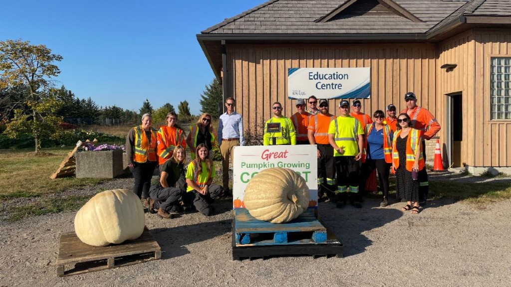 People stand near a giant pumpkin for a photo