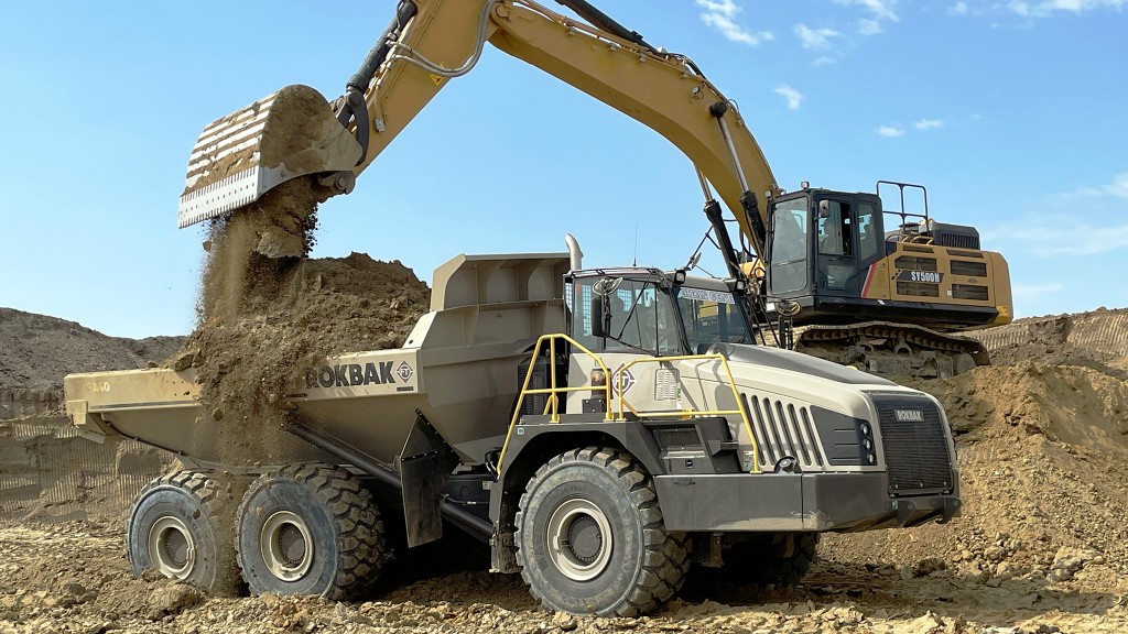 An articulated hauler being loaded by an excavator in a gravel pit.