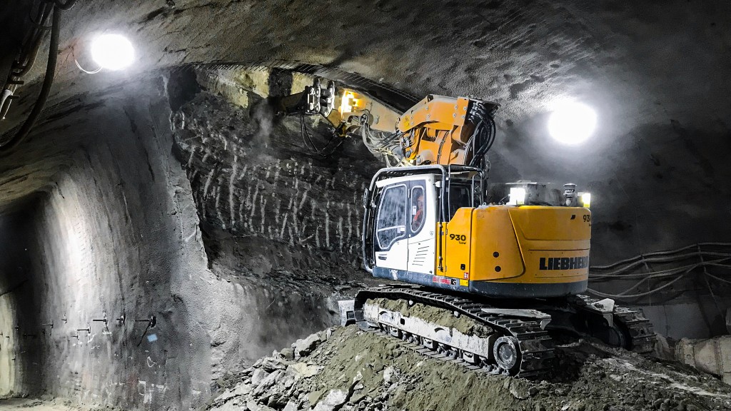 An excavator working in a rocky tunnel.